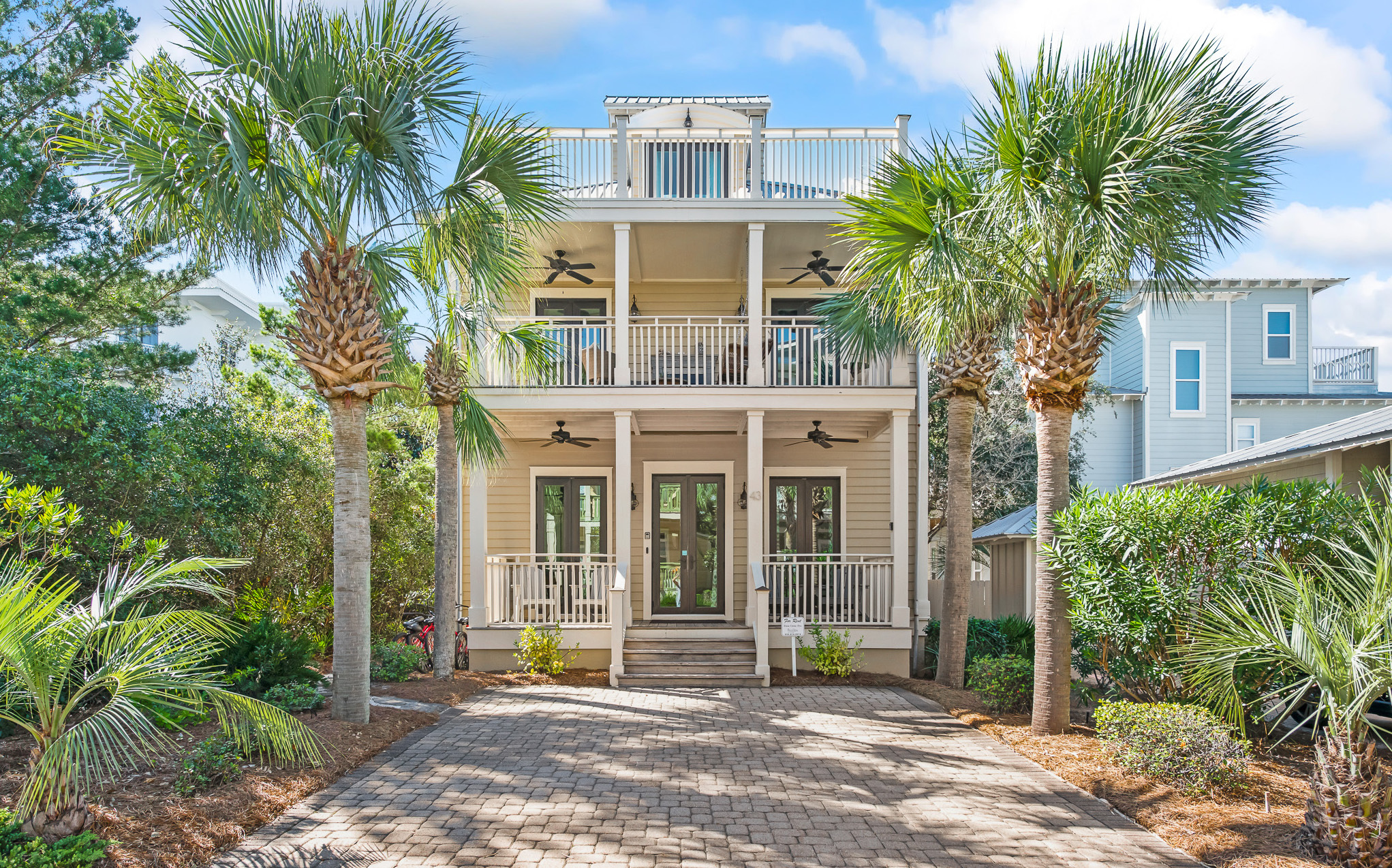 A two story beach cottage in Seacrest Beach with majestic palm trees